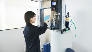 Laboratory specialist operating a high-throughput blood sample analysis instrument, photograph.