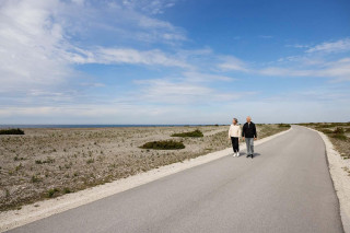 Two people walking along a road through an open landscape, photograph.