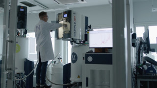 Laboratory professional operating a nuclear magnetic resonance spectroscopy instrument, photograph.