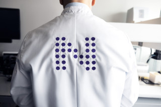 Laboratory specialist wearing a lab coat with Nightingale Health logo in the back.